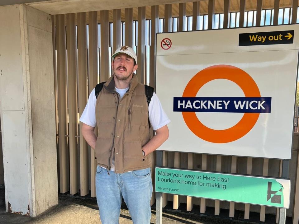 Burton vor einem Schild in der U-Bahn für eine Haltestelle in East London.  - Copyright: Courtesy of Michael Burton