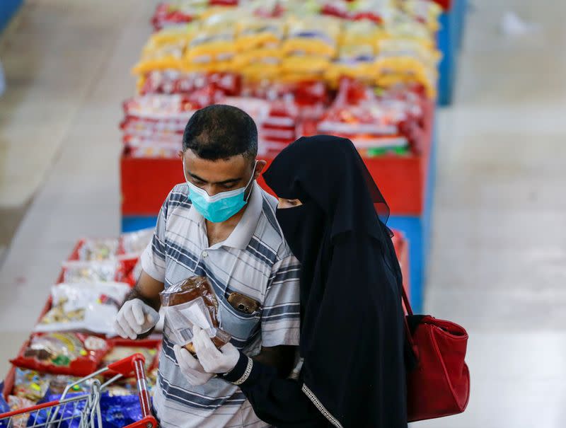 FILE PHOTO: Couple wearing protective face masks and gloves shop at a supermarket amid concerns of the spread of the coronavirus disease (COVID-19), in Sanaa