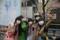 Fans wearing masks pose for photos before the start of a concert by Japanese girl group Perfume outside Tokyo Dome in Tokyo, Tuesday, Feb. 25, 2020. Japan's Prime Minister Shinzo Abe said Tuesday that new measures like companies letting their employees work from home and hospitals expanding their capacity to treat many patients will determine if Japan could control its coronavirus outbreak. (AP Photo/Jae C. Hong)