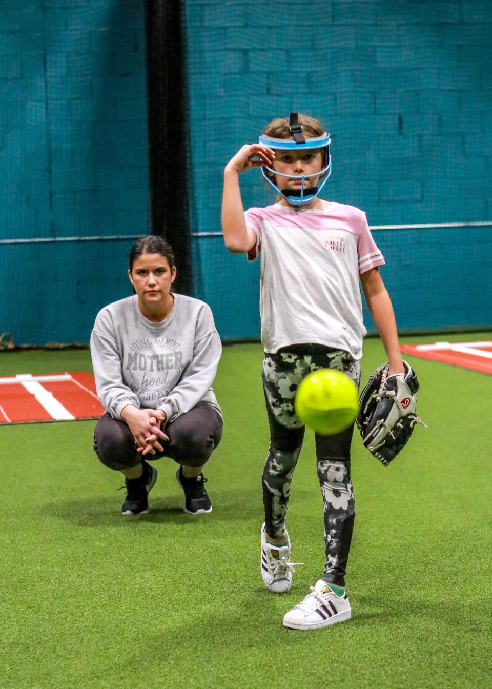 Sophia Almeida delivers a pitch under the watchful eye of her pitching instructor Ashley Ambrose at the new location of Inside The Park Batting Cages in New Bedford