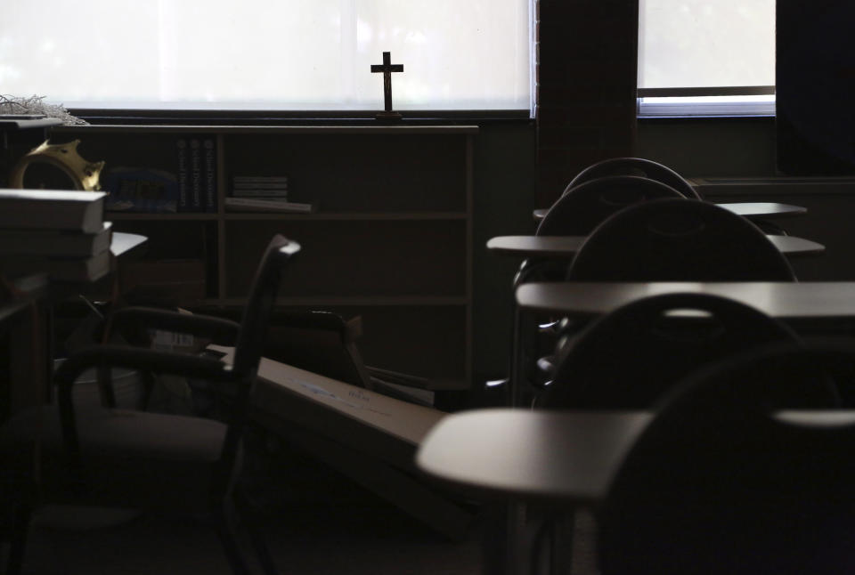 A cross sits in the window of an empty classroom at Quigley Catholic High School in Baden, Pa., Monday, June 8, 2020. Pittsburgh Bishop David Zubik recently announced the school's closure, saying the decision was based on declining enrollment, unsustainable cost projections and insufficient funds to assure its long-term viability. (AP Photo/Jessie Wardarski)