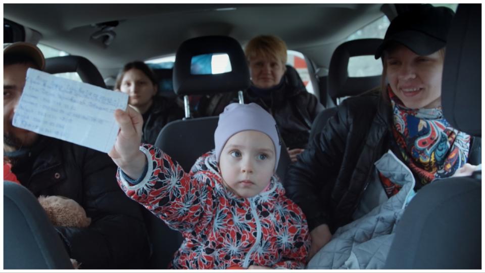 A Ukrainian child holds a paper with vital information about her in case she becomes a victim of Russian bombing.