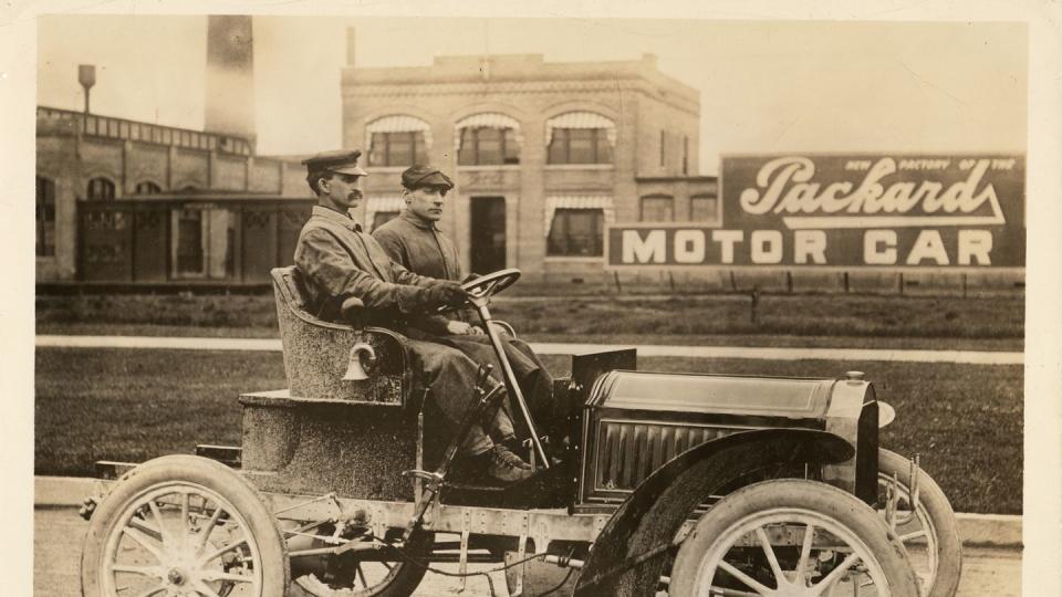 1904 packard model l with driver and passenger in front of packard plant in detroit