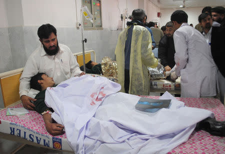 A man comforts his son, who was injured during an attack by Taliban gunmen on the Army Public School, at Lady Reading Hospital in Peshawar, December 16, 2014. REUTERS/Stringer