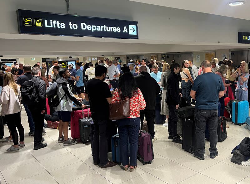 Passengers queue outside Terminal 1 after an overnight power cut led to disruptions and cancellations at Manchester Airport in Manchester