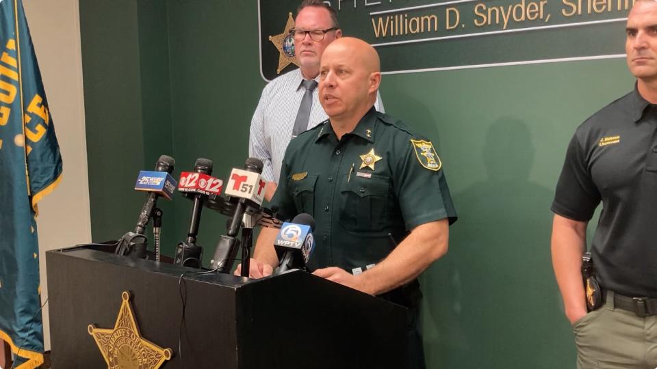 Martin County Sheriff's Chief Deputy John Budensiek stands at the podium; Detective Brian Broughton is behind him.