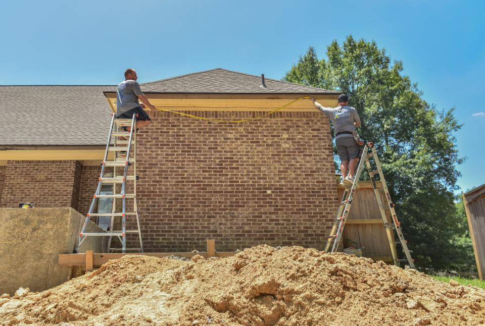 Gary Wilkenson, 28 (left), and Zach Clanton, 33, work outside for Complete Exteriors in the heat in Brandon, Miss., Tuesday, June 21, 2022. 