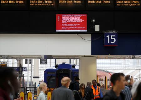 Passengers walk past a screen warning of disruption on one of the main railway lines into Waterloo station in central London, Britain July 24, 2017. REUTERS/Peter Nicholls