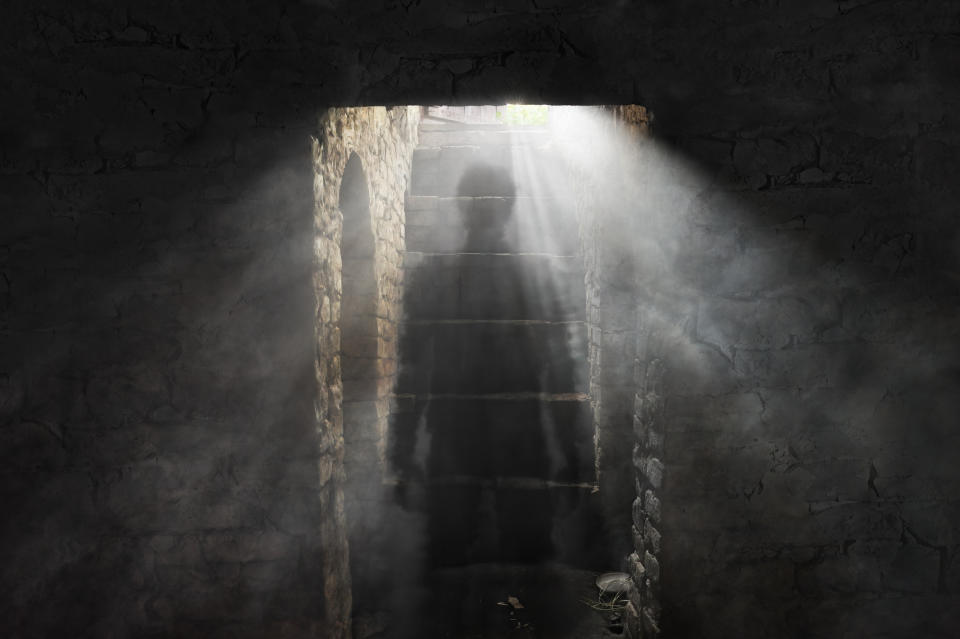 Person climbing stairs towards light in a dimly lit, brick-lined tunnel