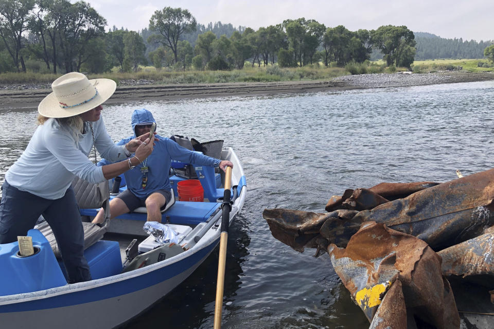 Wendy Weaver with Montana Freshwater Partners, left, photographs a piece of a railroad tank car in the Yellowstone River, Monday, Aug. 21, 2023, near Reed Point, Mont. The piece was located about a mile downstream of a June 2023 train derailment that sent carloads of petroleum products plunging into the river. (AP Photo/Matthew Brown)