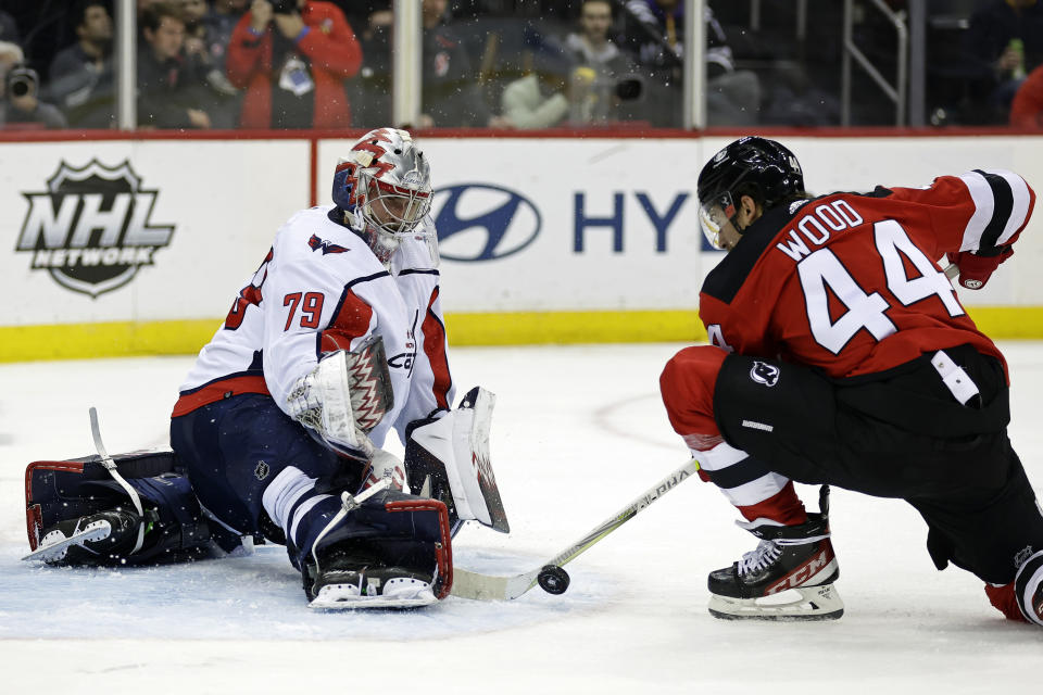 Washington Capitals goaltender Charlie Lindgren, left, makes a save against New Jersey Devils left wing Miles Wood (44) in the second period of an NHL hockey game Monday, Oct. 24, 2022, in Newark, N.J. (AP Photo/Adam Hunger)