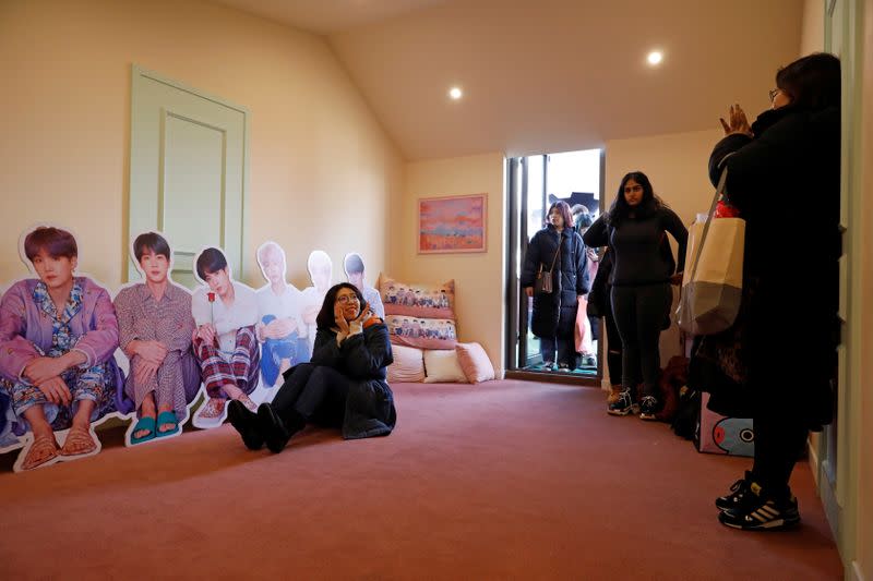 A fan of K-pop idol boy band BTS poses for photographs with cut-out of BTS at a pop-up store selling BTS goods in Seoul