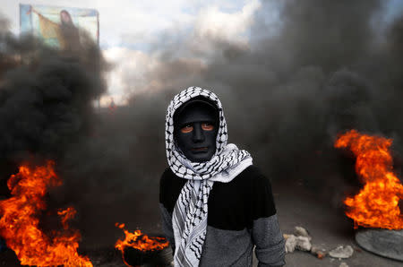 A Palestinian demonstrator stands near burning tires during clashes with Israeli troops at a protest against U.S. President Donald Trump's decision to recognise Jerusalem as the capital of Israel, near the West Bank city of Nablus December 15, 2017. REUTERS/Mohamad Torokman