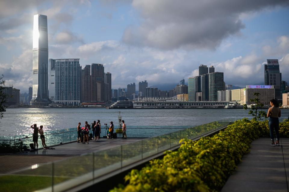 People gather to watch the sunset as they stand on a viewing platform in Tamar Park overlooking Victoria Harbour and the Kowloon skyline in Hong Kong on May 5, 2020. - Hong Kong on May 5 announced plans to ease major social distancing measures, including reopening schools, cinemas, bars and beauty parlours after the Chinese territory largely halted local transmission of the deadly coronavirus. (Photo by Anthony WALLACE / AFP) (Photo by ANTHONY WALLACE/AFP via Getty Images)