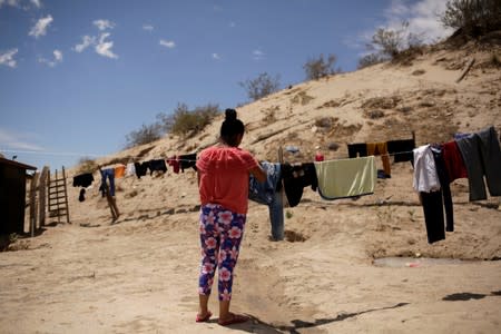 A Central American migrant hangs her clothes at the 'Aposento Alto' provisional shelter, on the outskirts of Ciudad Juarez