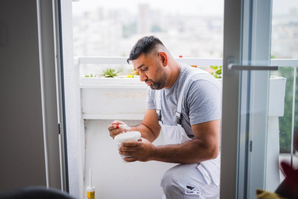 A man dressed in grey examines a product during a DIY project.