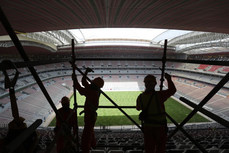 FILE - Laborers remove scaffolding at the Al Bayt stadium in Al Khor, Qatar, about 50 kilometers (30 miles) north of Doha, Monday, April 29, 2019. Migrant laborers who built Qatar's World Cup stadiums often worked long hours under harsh conditions and were subjected to discrimination, wage theft and other abuses as their employers evaded accountability, a rights group said in a report released Thursday. (AP Photo/Kamran Jebreili, File)