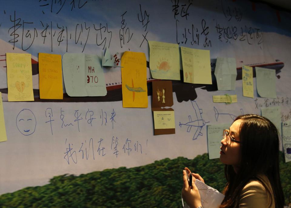 A woman looks at messages dedicated to passengers aboard Malaysia Airlines flight MH370 and their family members in Beijing