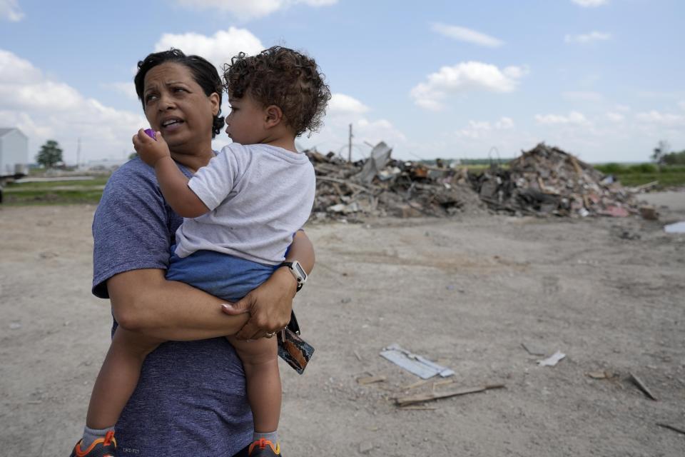 Tracy Harden, owner of Chuck's Dairy Bar, stands with her grandson Thomas Walker, 2, amid the rubble of her business and Chuck's Trailer Park, which were completely destroyed by a deadly tornado in Rolling Fork, Miss., Tuesday, May 9, 2023. An AP analysis shows that tornadoes are disproportionately killing more people in mobile or manufactured homes, especially in the South. (AP Photo/Gerald Herbert)