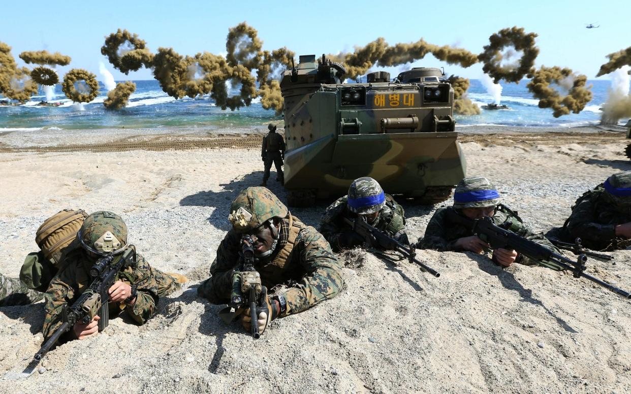 US Marines, left, and South Korean Marines, wearing blue headbands on their helmets, take positions after landing on the beach during a joint military exercise in 2016 - AP