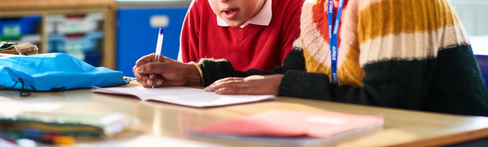 Female support worker assisting child in classroom