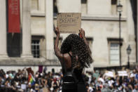 A woman holds up a banner as people gather in Trafalgar Square in central London on Sunday, May 31, 2020 to protest against the recent killing of George Floyd by police officers in Minneapolis that has led to protests across the US. (AP Photo/Matt Dunham)