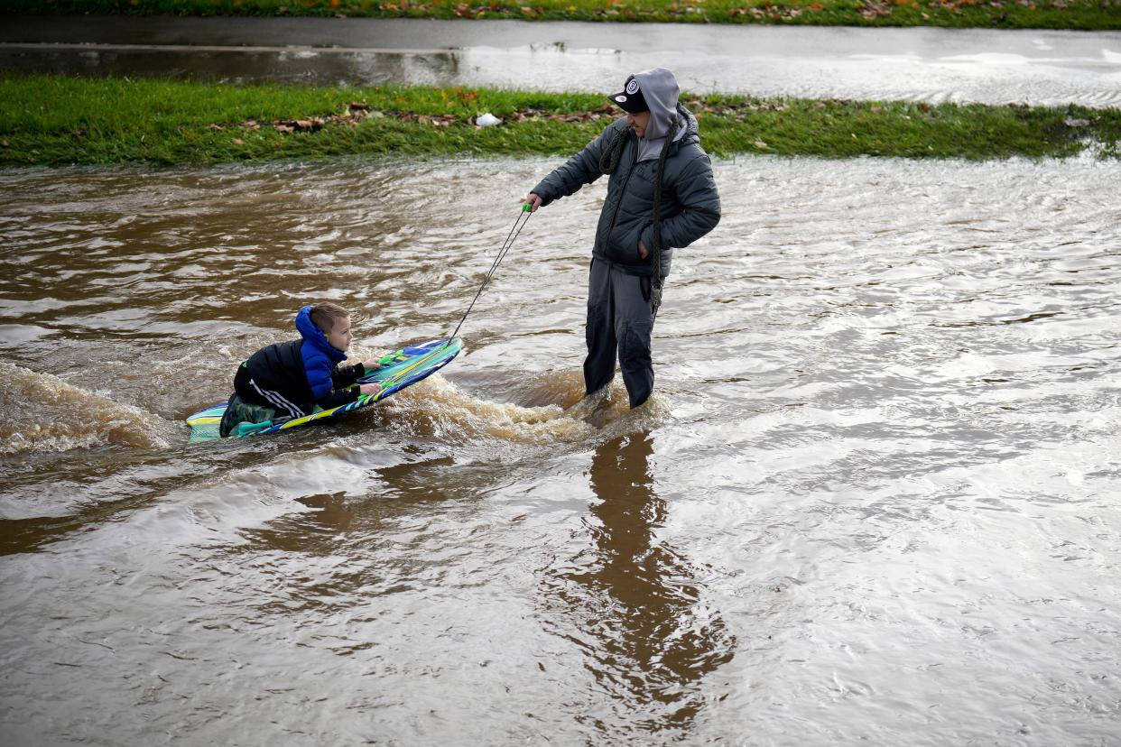 A man pulls a boy through flood water on a body board (Getty Images)