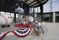 A man places flowers next to a portrait Atlanta Braves' Hank Aaron outside Truist Park, Friday, Jan. 22, 2021, in Atlanta. Aaron, who endured racist threats with stoic dignity during his pursuit of Babe Ruth but went on to break the career home run record in the pre-steroids era, died peacefully in his sleep early Friday. He was 86. (AP Photo/John Bazemore