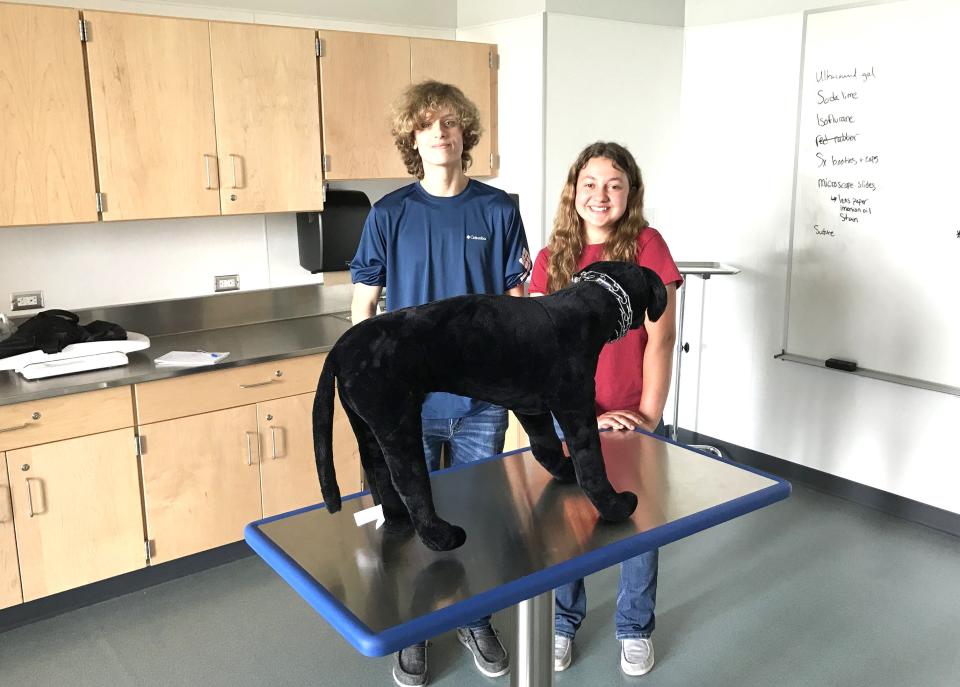Bristol County Agricultural High School sophomores Shayn Jones and Sarah Ashley describe the function of a brand new veterinary exam room next to a mannequin dog on May 23, 2023.