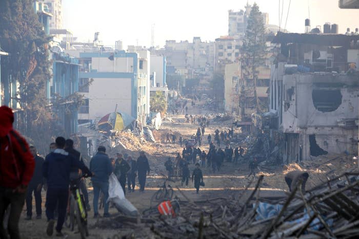 bombed building that palestinians are walking through to get to safety