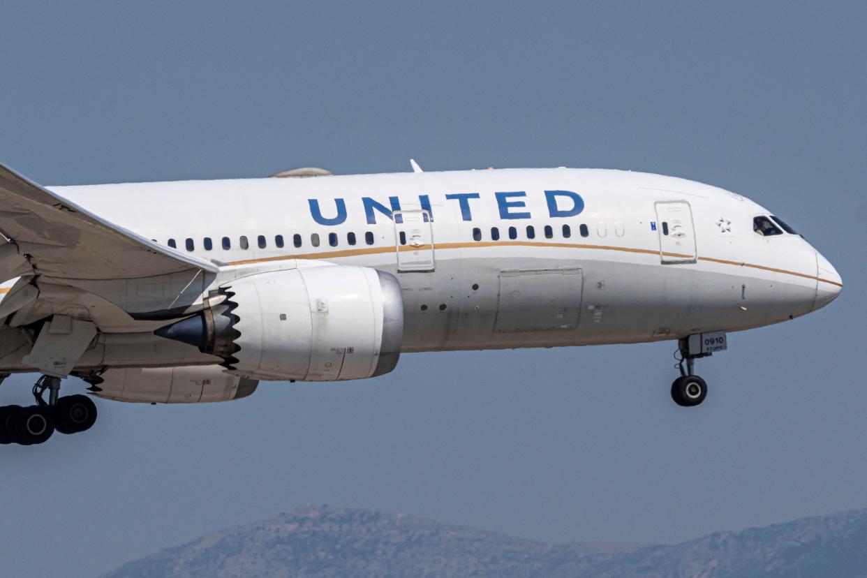 A United Airlines plane flying with its landing gear down.