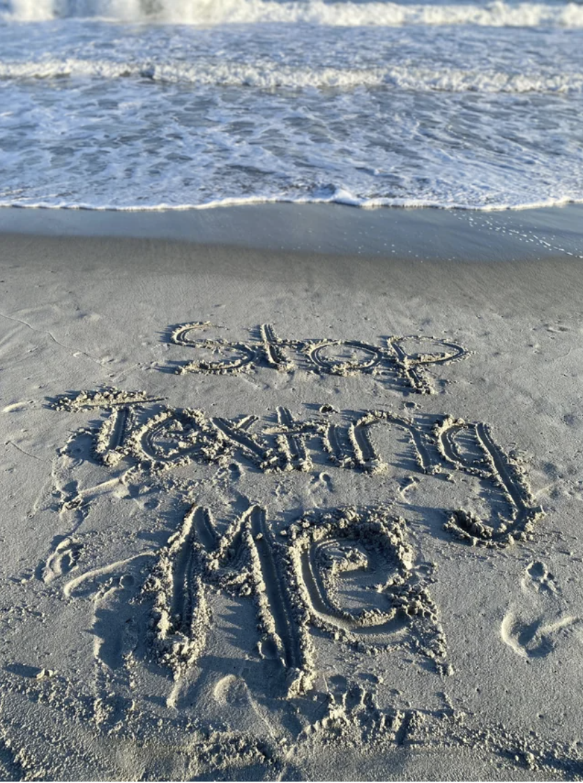 "Stop texting me" written in the sand