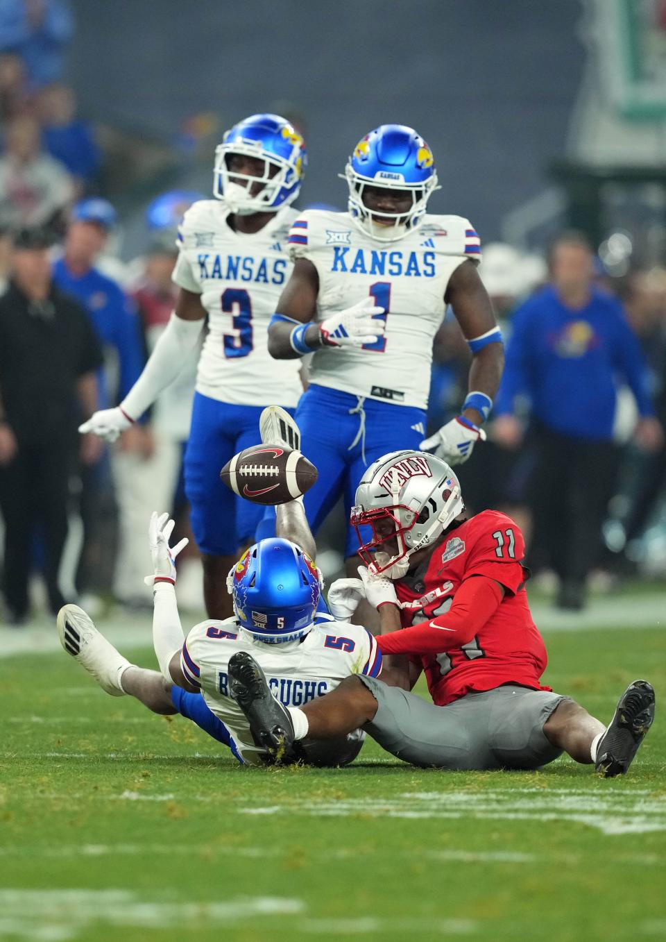 Dec 26, 2023; Phoenix, AZ, USA; Kansas Jayhawks wide receiver Luke Grimm (11) and UNLV Rebels linebacker Zavier Carter (11) go after the ball during the first half at Chase Field. Mandatory Credit: Joe Camporeale-USA TODAY Sports