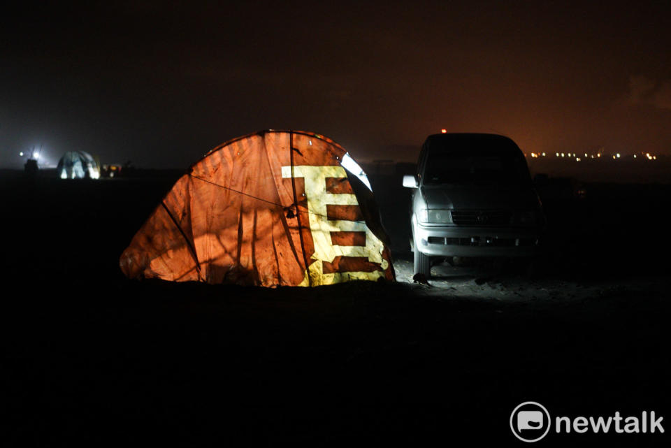 入夜後，一個用建案廣告帆布包覆的魚寮亮起燈火。   圖：張良一/攝