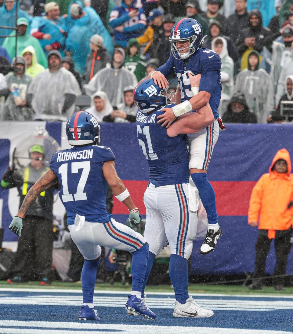 Oct 29, 2023; East Rutherford, New Jersey, USA; New York Giants quarterback Tommy DeVito (15) celebrates his rushing touchdown with center John Michael Schmitz Jr. (61) and wide receiver Wan'Dale Robinson (17) during the second half against the New York Jets at MetLife Stadium. Mandatory Credit: Vincent Carchietta-USA TODAY Sports