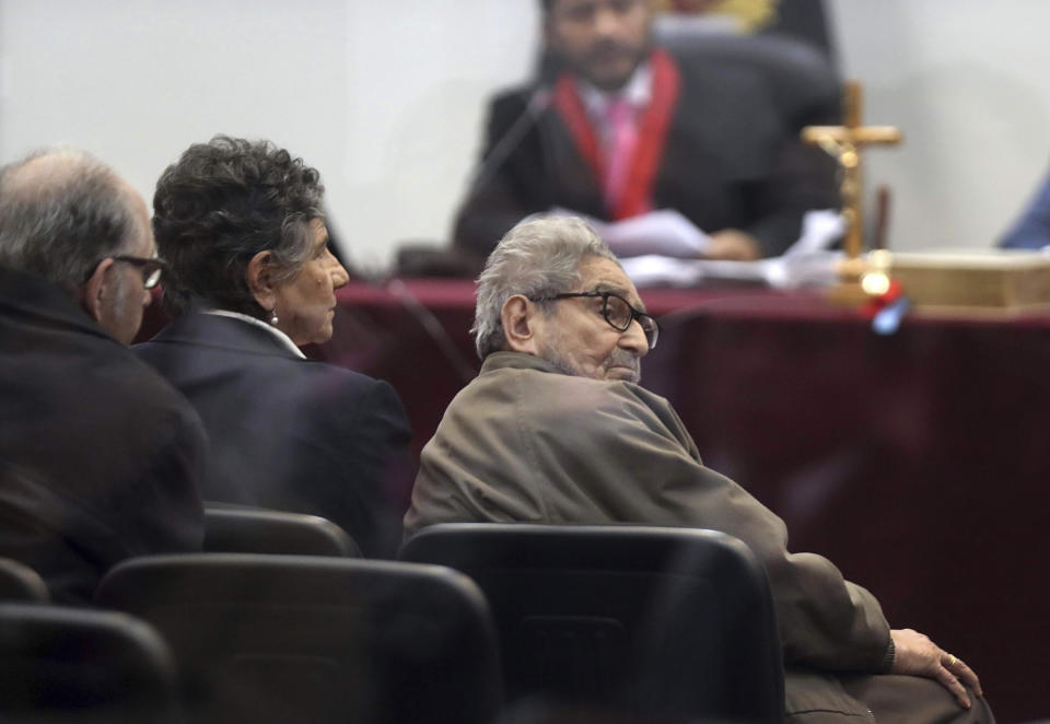 In this photo taken through a window, Abimael Guzman, founder and leader of the Shining Path guerrilla movement, looks at his lawyer while siting with his partner Elena Iparraguirre, during the sentencing phase of their trial at a naval base in Callao, Peru, Tuesday, Sept. 11, 2018. On Tuesday, the historic leader of the terrorist group Shining Path and Iparraguirre will be sentenced for their role in a 1992 car bomb that killed 25 people in Lima. (AP Photo/Martin Mejia)