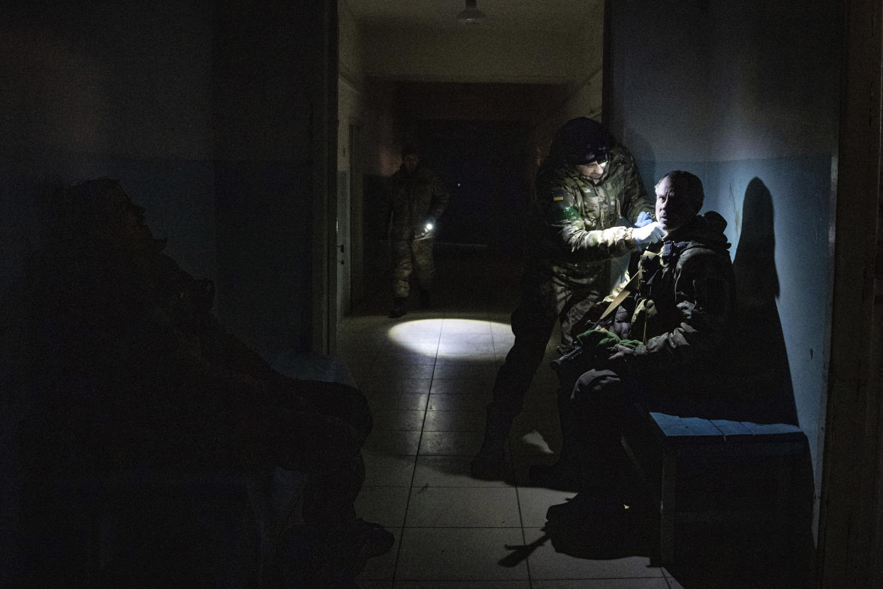 A Ukrainian military medic treats his injured comrade in the corridor of a hospital in Donetsk region, Ukraine, Monday, Jan. 9, 2023. (AP Photo/Evgeniy Maloletka)