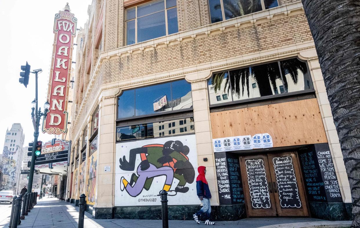 <p>A person walks by a boarded-up shop in Oakland, California on February 12, 2021. </p> ((Photo by JOSH EDELSON / AFP) )