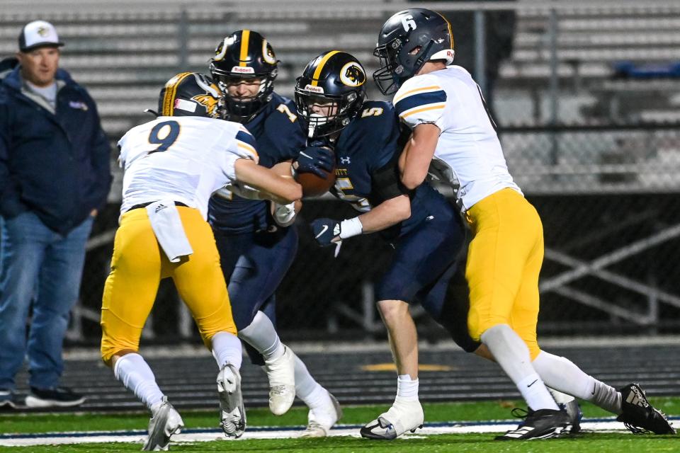 DeWitt's' Abram Larner, center, runs in to the end zone for a touchdown as Cadillac's Keenan Suminski, left, and Chris Reinhold try to make the stop during the first quarter on Friday, Oct. 28, 2022, at DeWitt High School.
