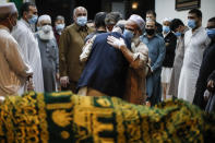 Mohammad Ayaz, cousin of Mohammad Altaf, center right, is hugged by a mourner after funeral prayers are given over Altaf's body at Al-Rayaan Muslim Funeral Services, Sunday, May 17, 2020, in the Brooklyn borough of New York. (AP Photo/John Minchillo)