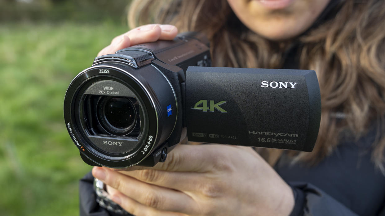  A front view of a photographer holding the Sony FDR-AX53 camcorder. 