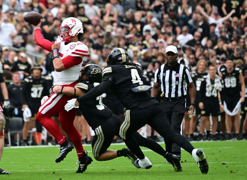 Sep 28, 2024; West Lafayette, Indiana, USA; Nebraska Cornhuskers quarterback Dylan Raiola (15) is tackled by Purdue Boilermakers defensive back Dillon Thieneman (31) and linebacker Kydran Jenkins (4) while throwing a pass during the second quarter at Ross-Ade Stadium.