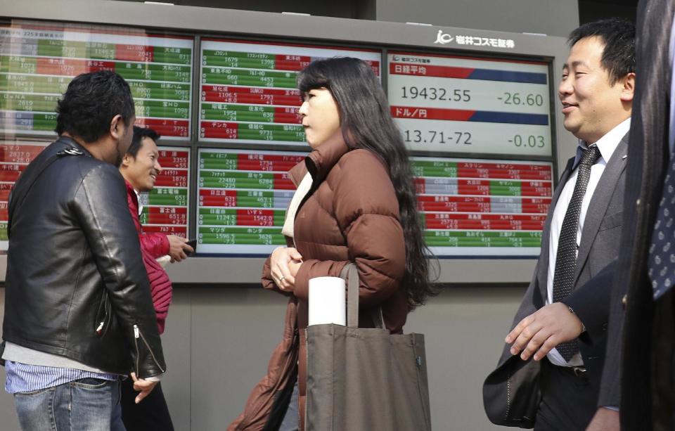 People walk past an electronic stock indicator of a securities firm in Tokyo, Tuesday, Feb. 14, 2017. Shares in Asia fell back after an early rally on Tuesday, as investors awaited comments to Congress by Federal Reserve chair Janet Yellen. (AP Photo/Shizuo Kambayashi)