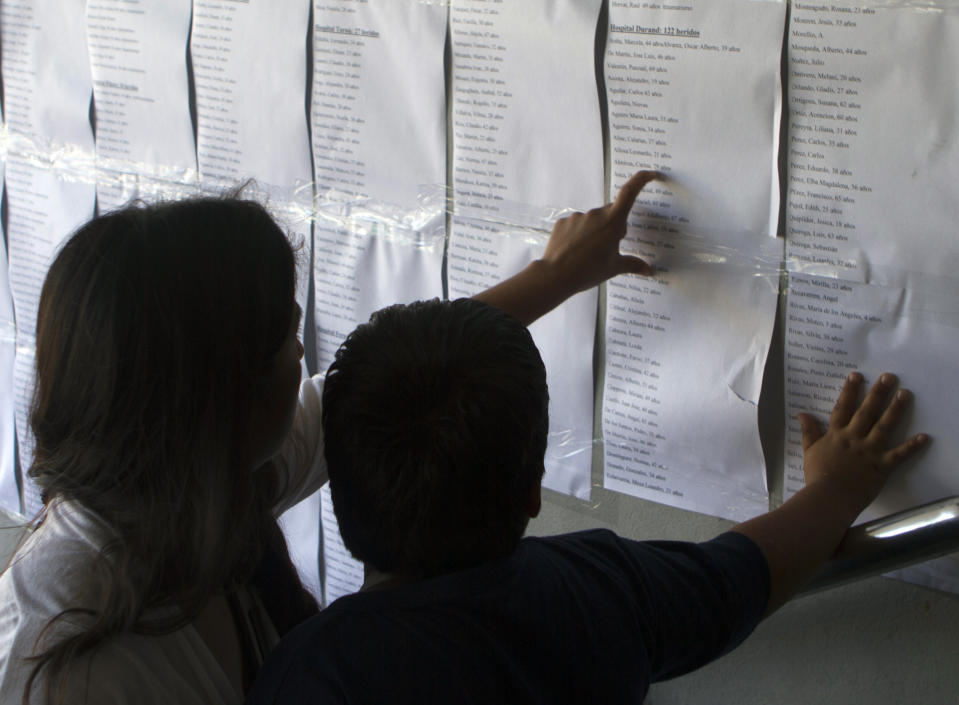 People look at lists of names informing what hospital injured commuters were sent to, posted outside the train station in Buenos Aires, Argentina, Thursday Feb. 23, 2012. Wednesday's commuter train crash killed dozens and sent hundreds to emergency rooms. A federal judge was leading an investigation into what caused the rush-hour commuter train to slam into a barrier at the end of the track at a downtown station, crumpling cars around hundreds of riders. (AP Photo/Eduardo Di Baia)