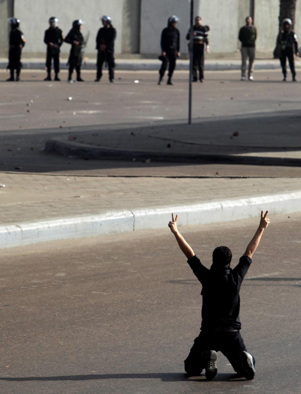 A protester flashes a victory sign in front of police during clashes in Cairo in January 2011REUTERS