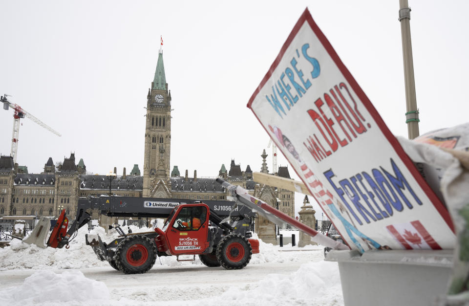 Machinery moves a concrete barricade past the Parliament buildings and a container of garbage from the trucker protest which has occupied the streets of Ottawa, Sunday, Feb. 20, 2022. (Adrian Wyld/The Canadian Press via AP)