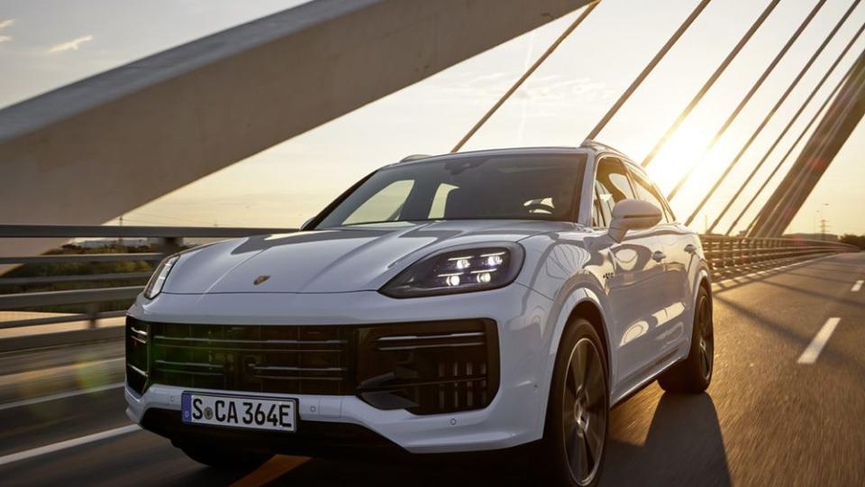 2024 porsche cayenne turbo ehybrid front end in white driving into sunset
