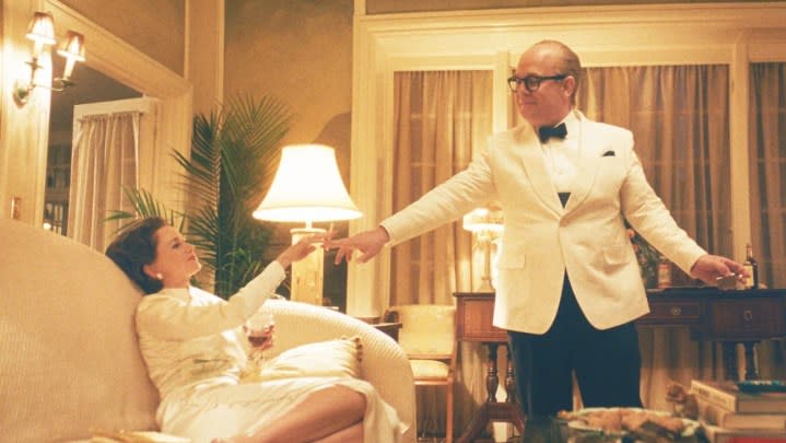 A man takes the hand of a woman in Feud: Capote vs. the Swans.