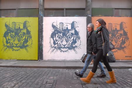 Pedestrians walk past graffiti in Dublin, Ireland February 18, 2016. REUTERS/Clodagh Kilcoyne