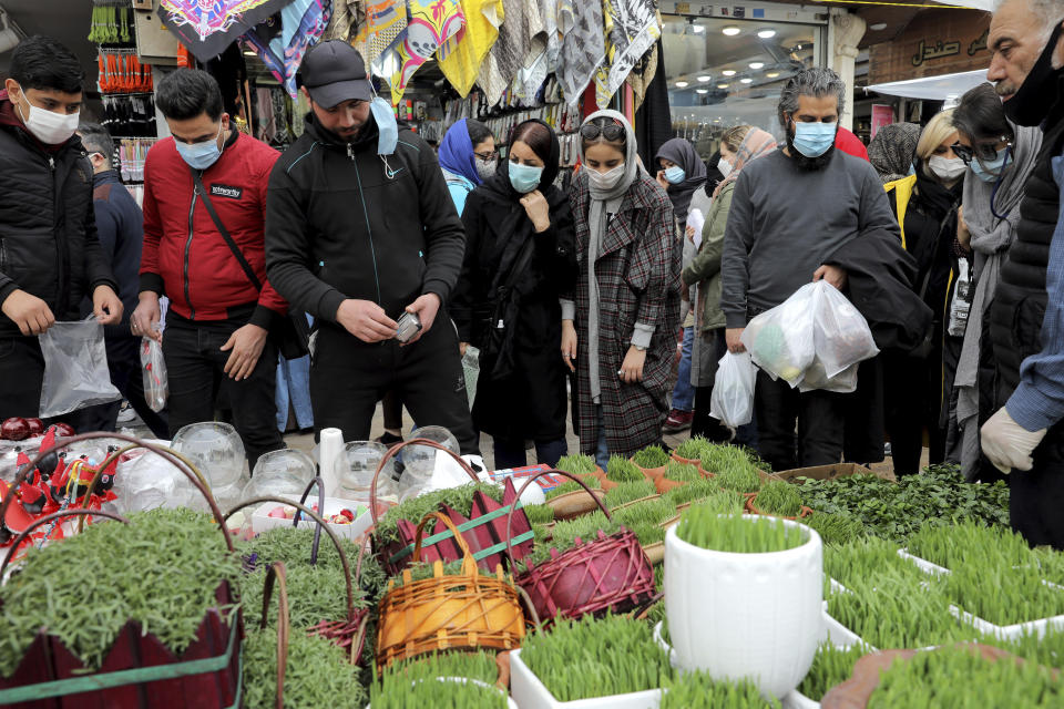 Potential customers look at baskets of grass shoots, an item of the Persian New Year, or Nowruz, meaning "New Day." in northern Tajrish Square, Tehran, Iran, Wednesday, March 17, 2021. (AP Photo/Ebrahim Noroozi)